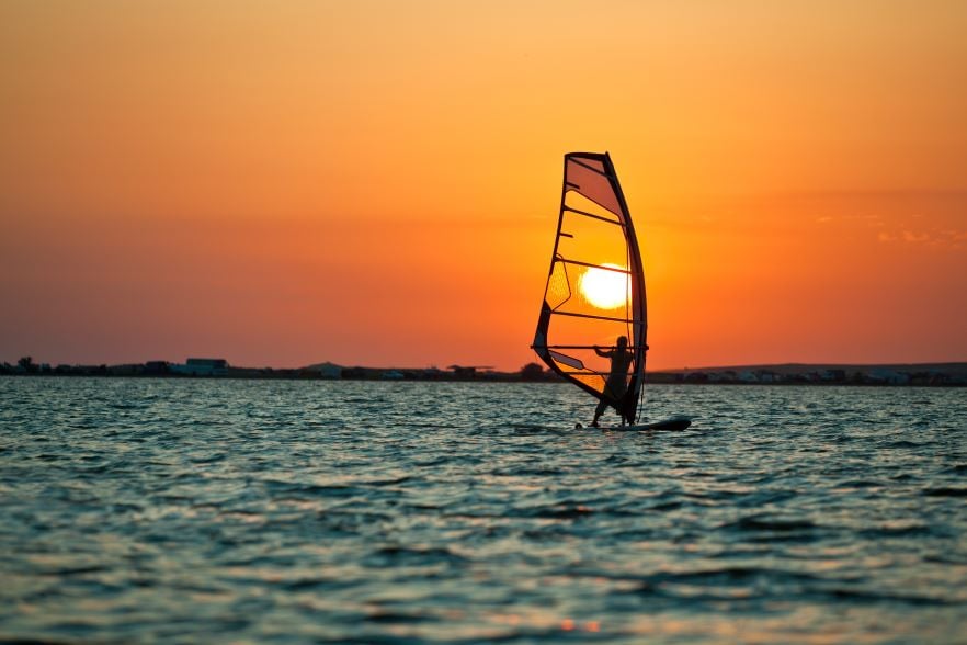 still-sea-surface-man-practicing-wind-surfing